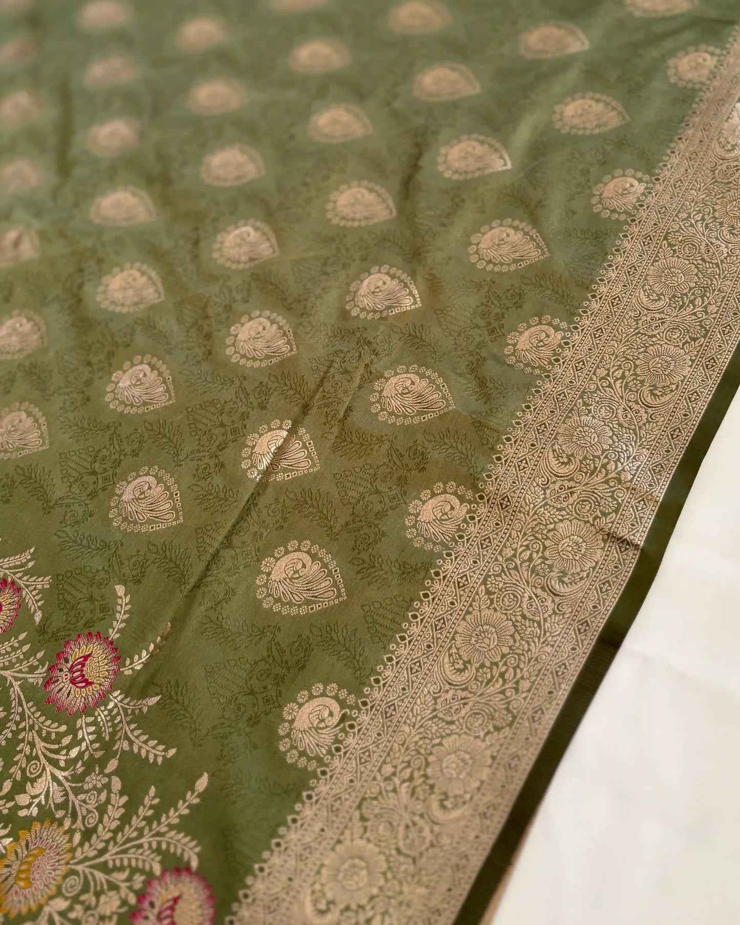 Green fabric with intricate patterns and embroidery on a white background