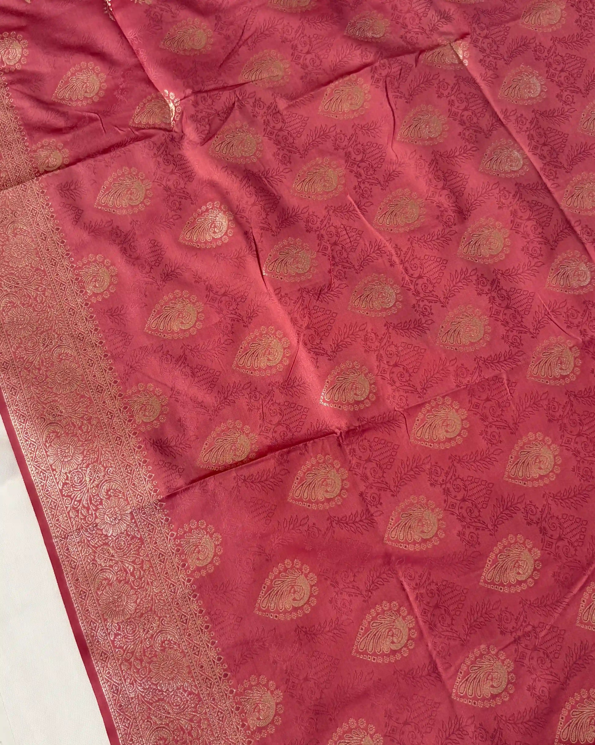 Pink fabric with gold embroidery on a white background