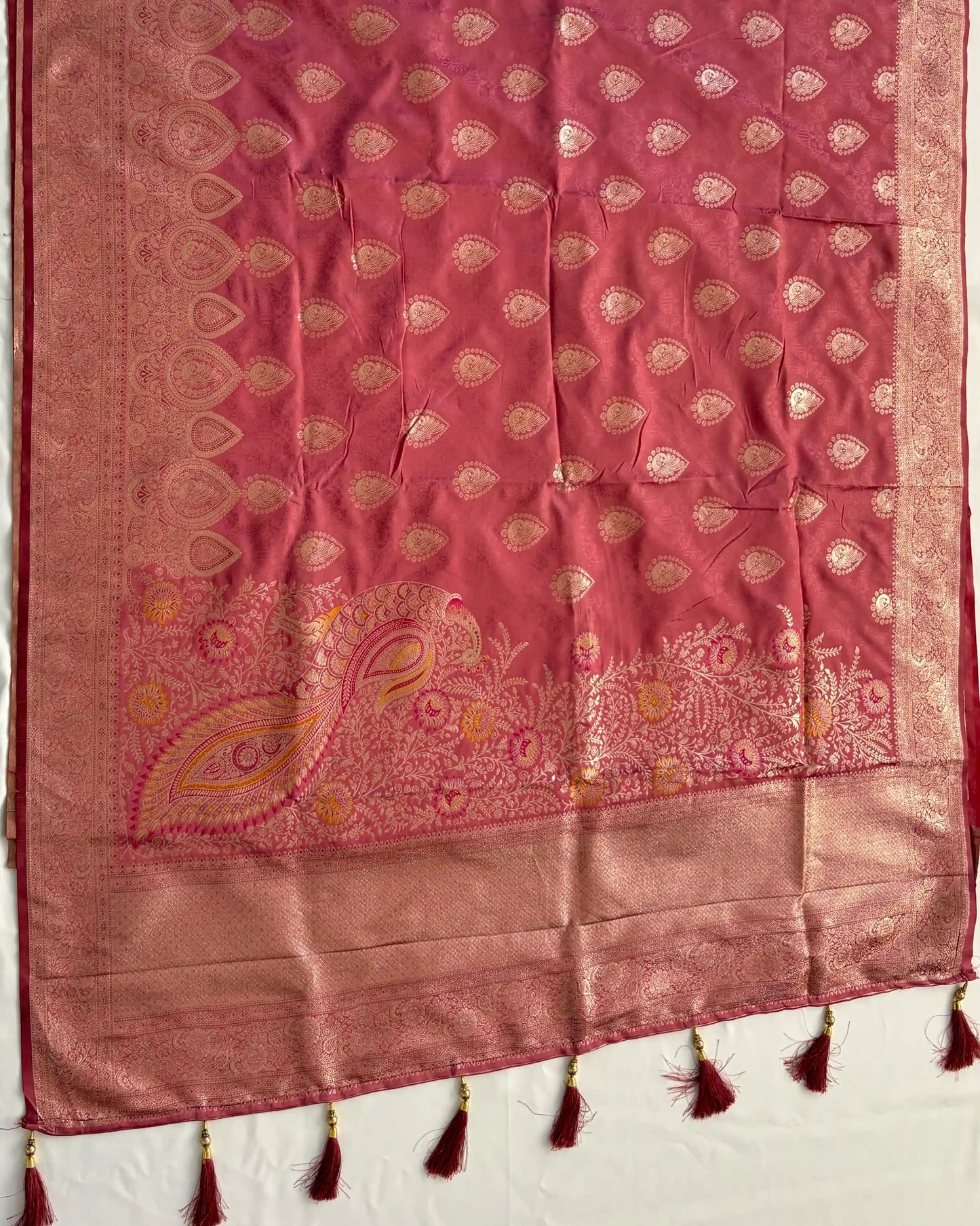 Pink fabric with gold embroidery and tassels on a white background