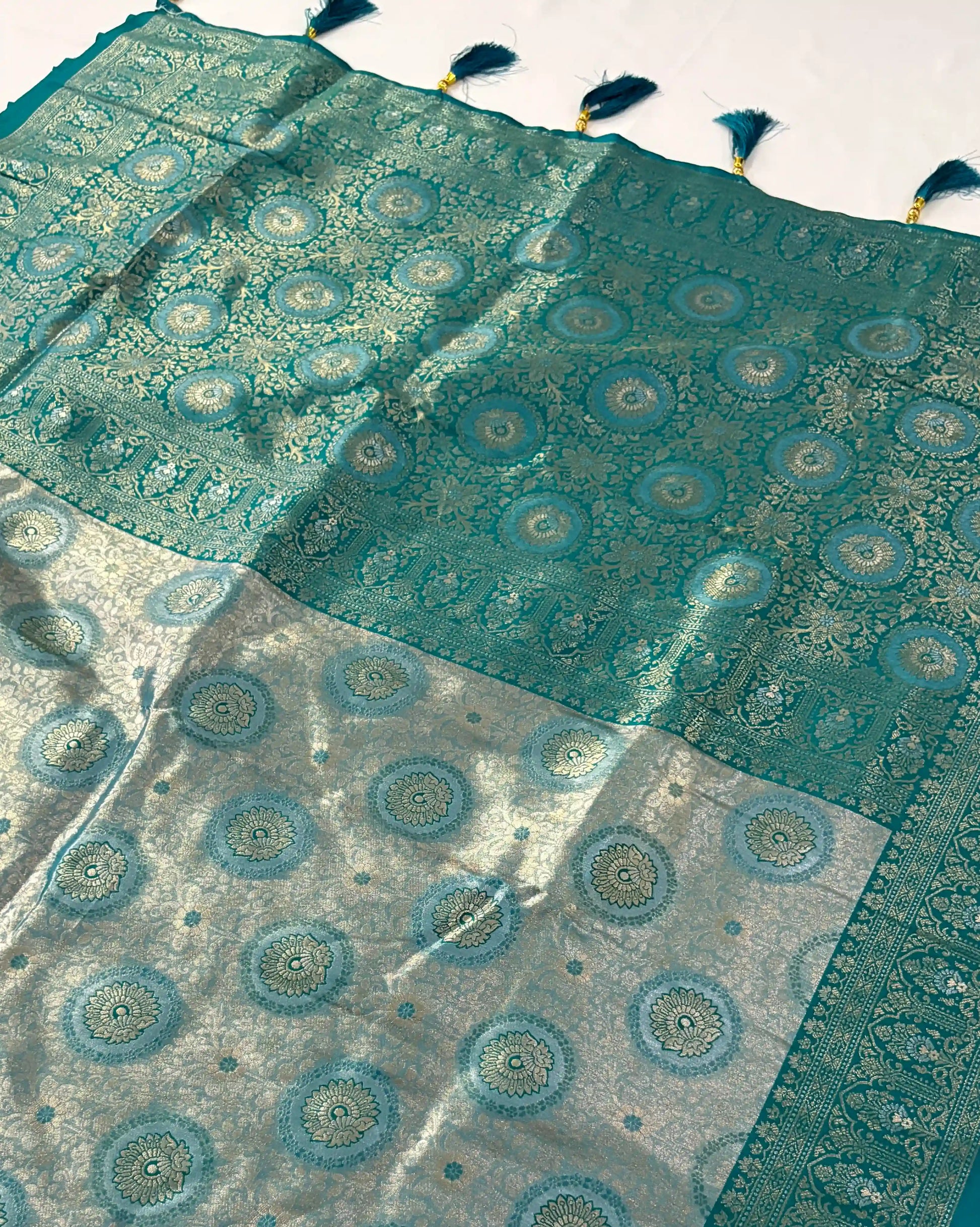 Teal and gray patterned fabric with tassels on a white background